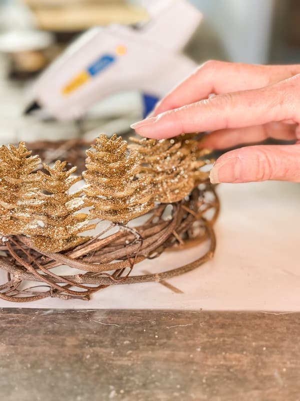 Add gold pinecones to grapevine ring