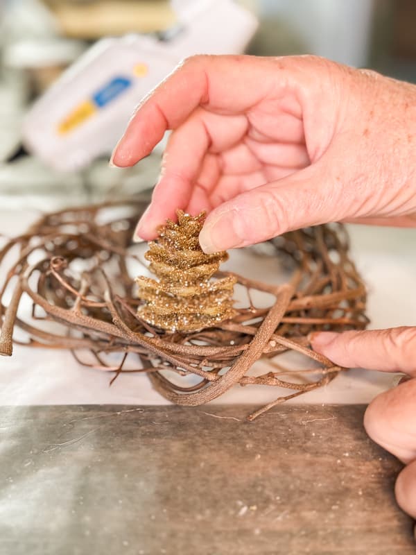 Press gold pinecone onto foraged grapevine ring.