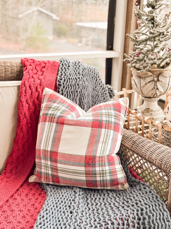 layer two throw blankets with red and white pillow on screened porch.  