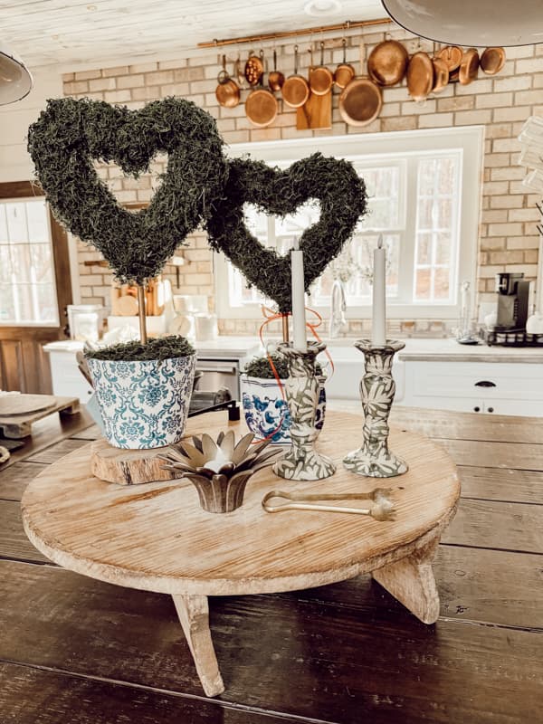 two Dollar Tree Valentine's Day Decor Heart Topiaries on Kitchen Island with Copper pots and brick wall background.