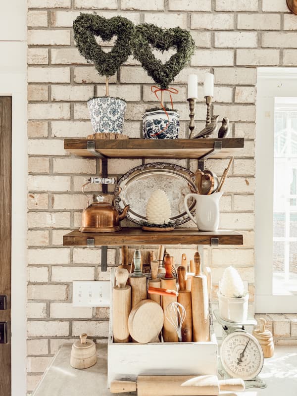 Two heart topiaries on open kitchen shelves with vintage brass, copper and silver accents.  