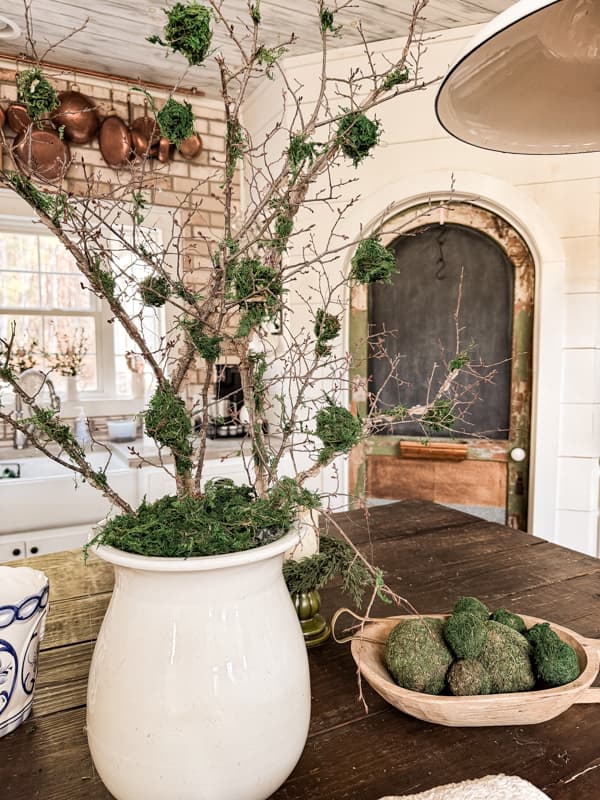 Moss Branches and Spheres in white ironstone vessel on kitchen island for Spring Decoratiing